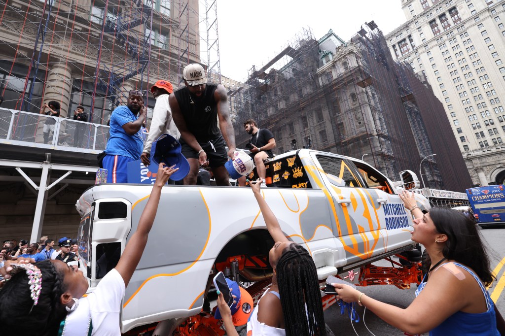 New York Knicks player Mitchell Robinson signs autographs for fans while celebrating the team's NBA championship during a ticker-tape parade down Lower Manhattan's "Canyon of Heroes" on Broadway, Thursday, June 18, 2026 in New York. 