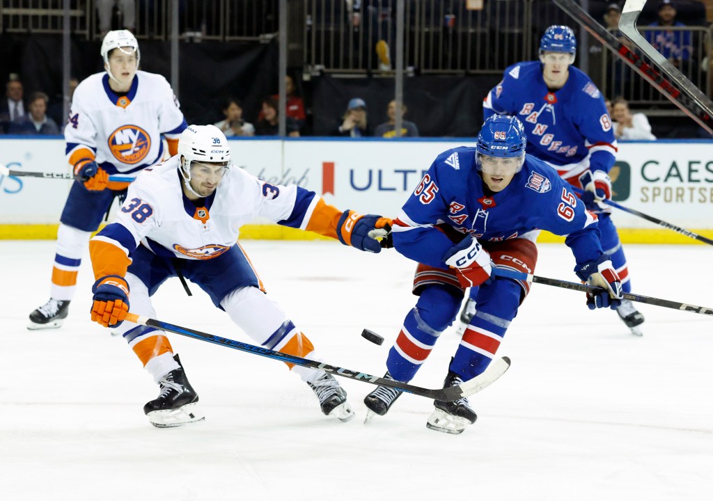 New York Rangers left wing Brett Berard (R) fighting for the puck with New York Islanders defenseman Travis Mitchell (L).