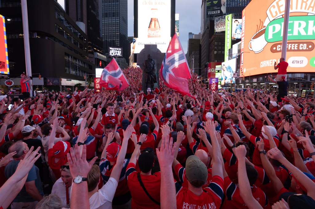 Norwegian national football team supporters with raised hands in Times Square before a World Cup match.