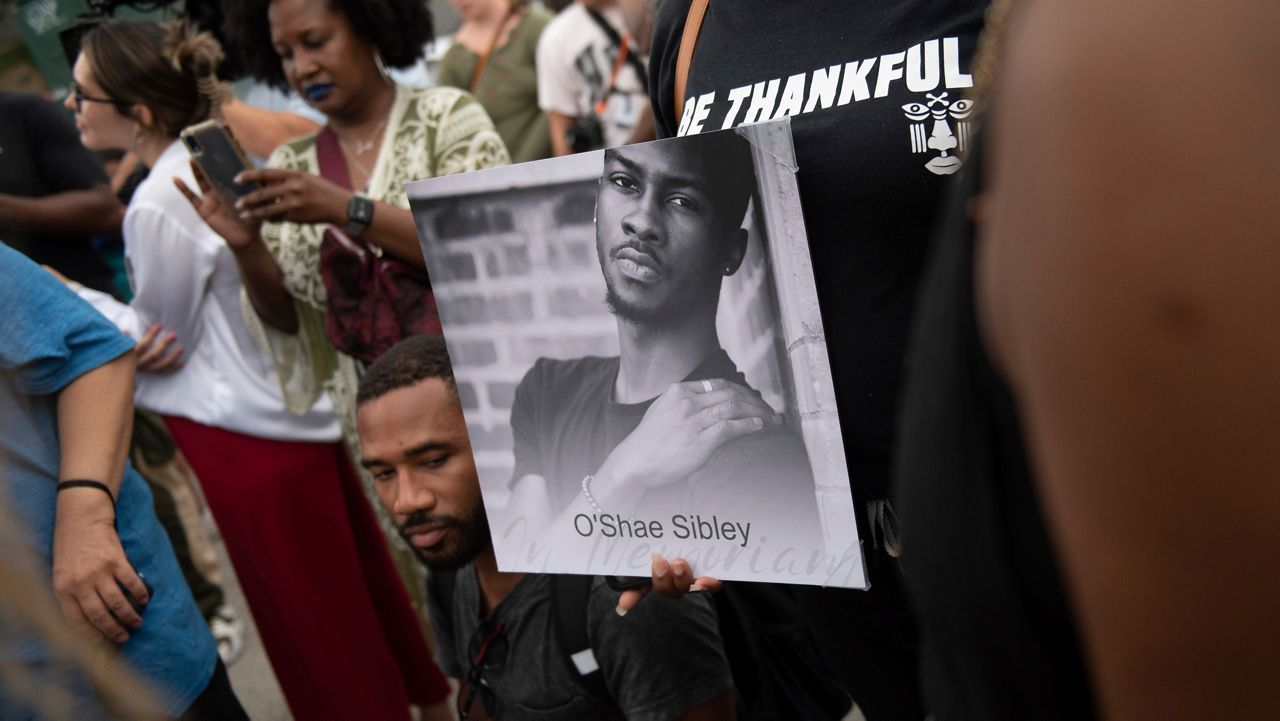 A person holds up a photo of O'Shae Sibley during a vigil at a gas station, Aug. 4, 2023, in the Brooklyn borough of New York. (AP Photo/Tracie Van Auken, File)