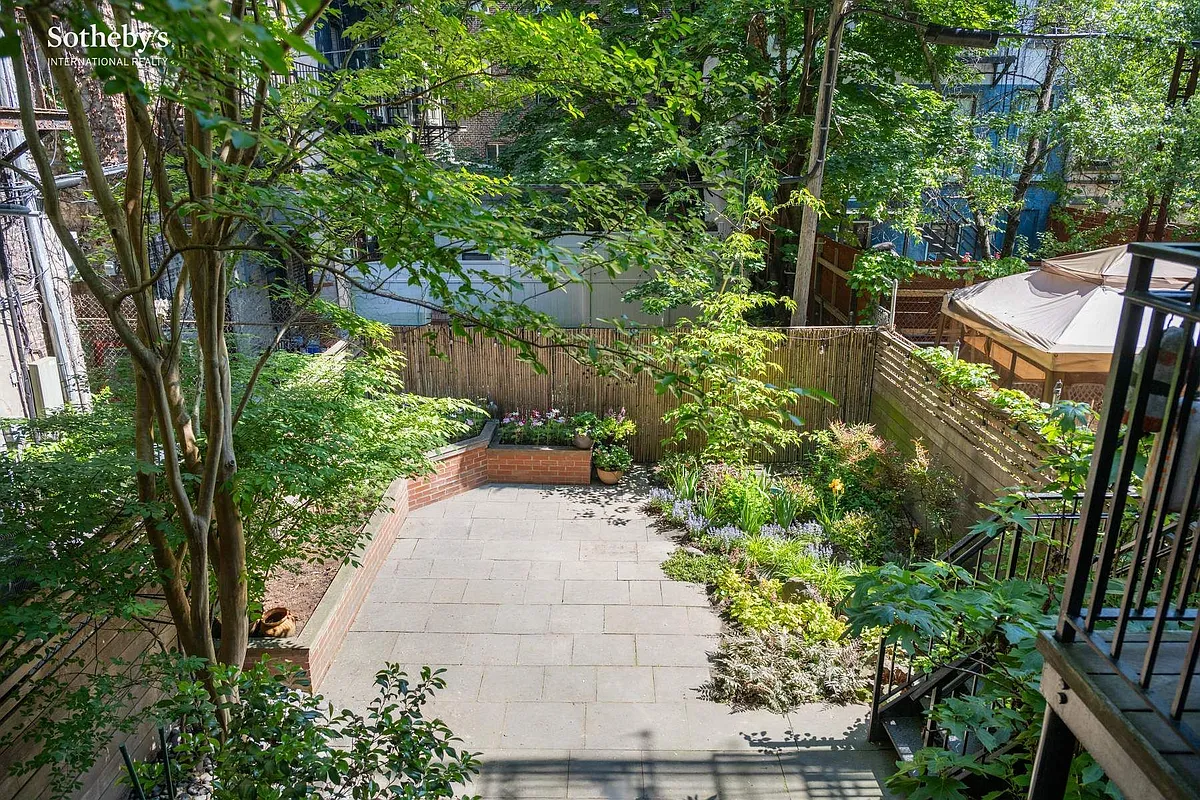 landscaped rear yard with raised planters, paved patio