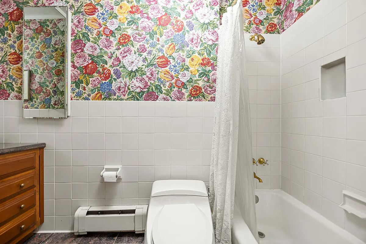 bathroom with floral wallpaper, white fixtures