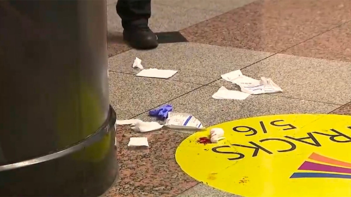 Debris, medical supplies and what appears to be blood are visible on the floor near a train platform area following a stabbing incident at New York City's Penn Station.