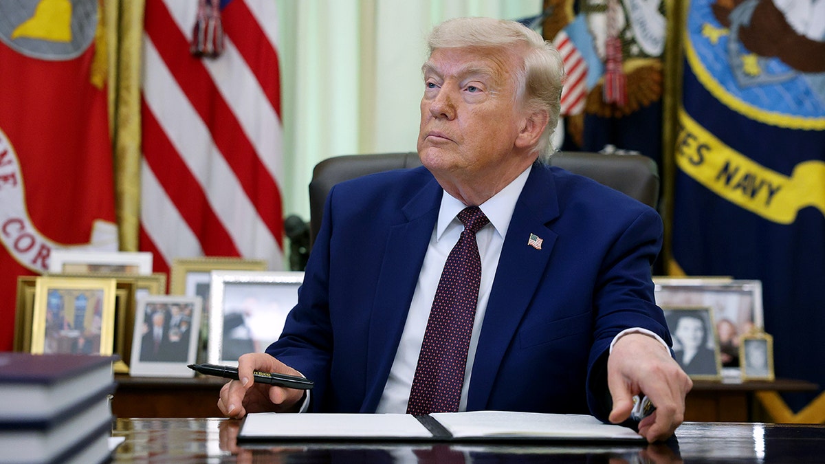 President Donald Trump signing an executive order in the Oval Office of the White House.