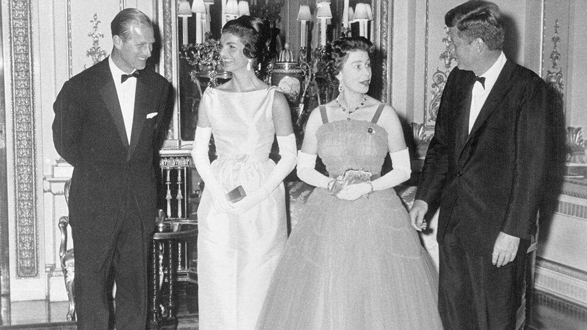 Prince Philip and President John F. Kennedy chatting with Jacqueline Kennedy and Queen Elizabeth at Buckingham Palace.