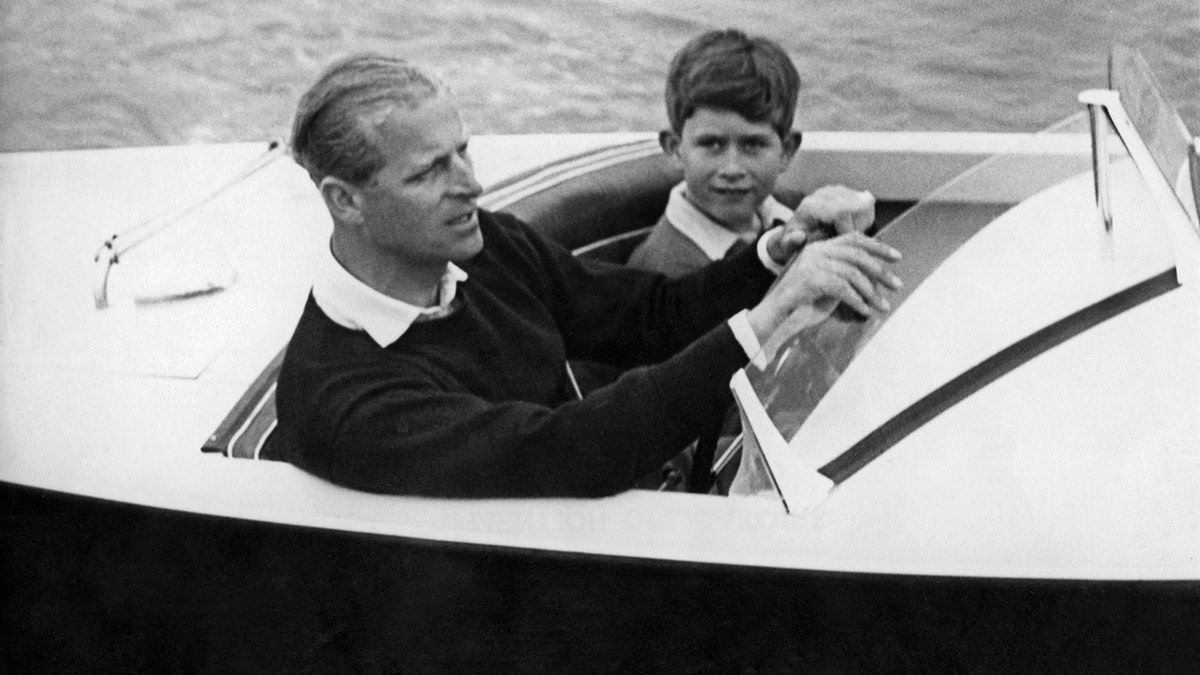 Prince Charles and Prince Philip standing on a boat in 1955
