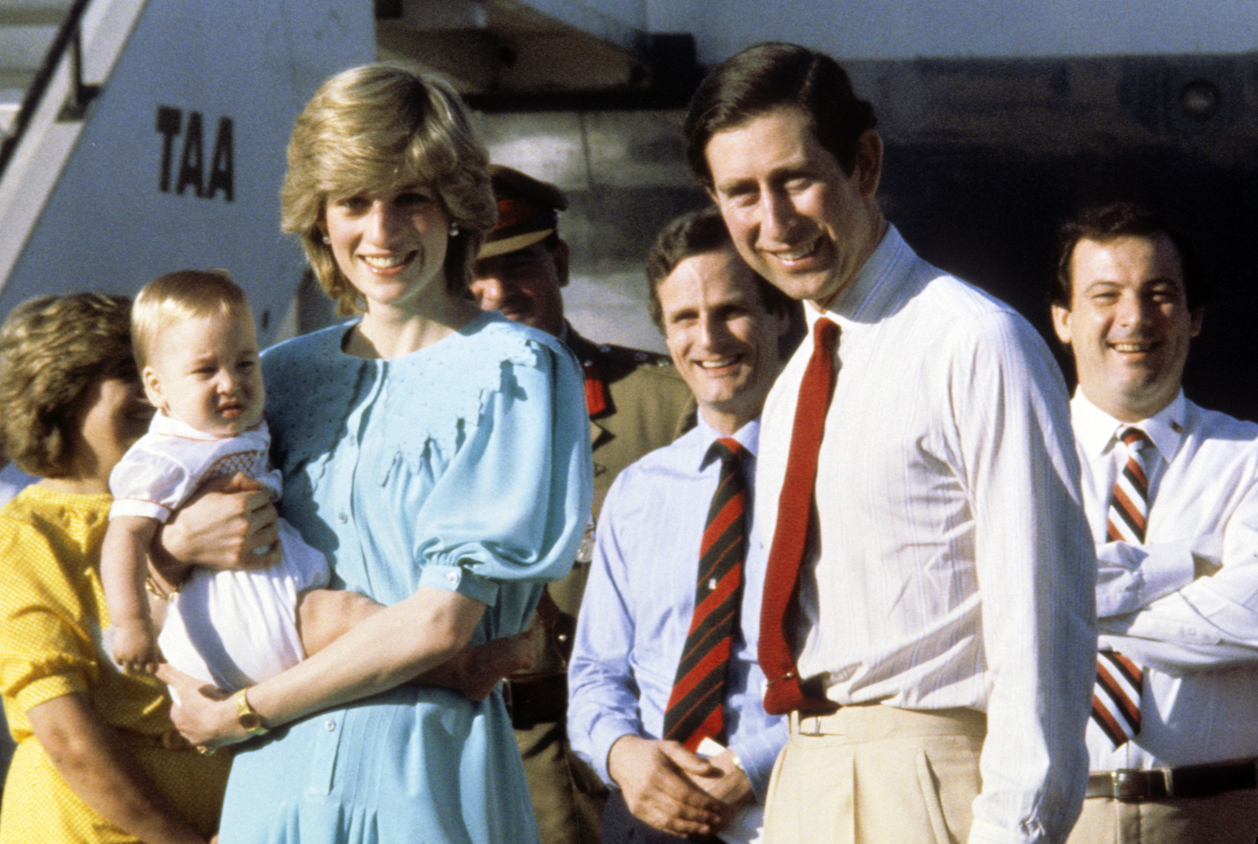Princess Diana wears a Jan Van Velden dress and holds baby Prince William, while standing alongside King Charles, as they arrive at Alice Springs Airport, Australia on March 20, 1983