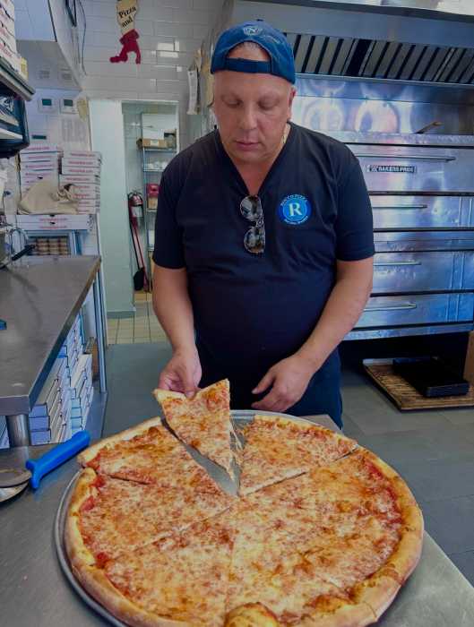 Man serving a slice of NYC pizza