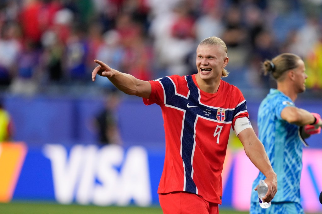 Norway's Erling Haaland smiling and pointing while leaving the field.
