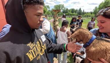 a young man pets a goat at a farm