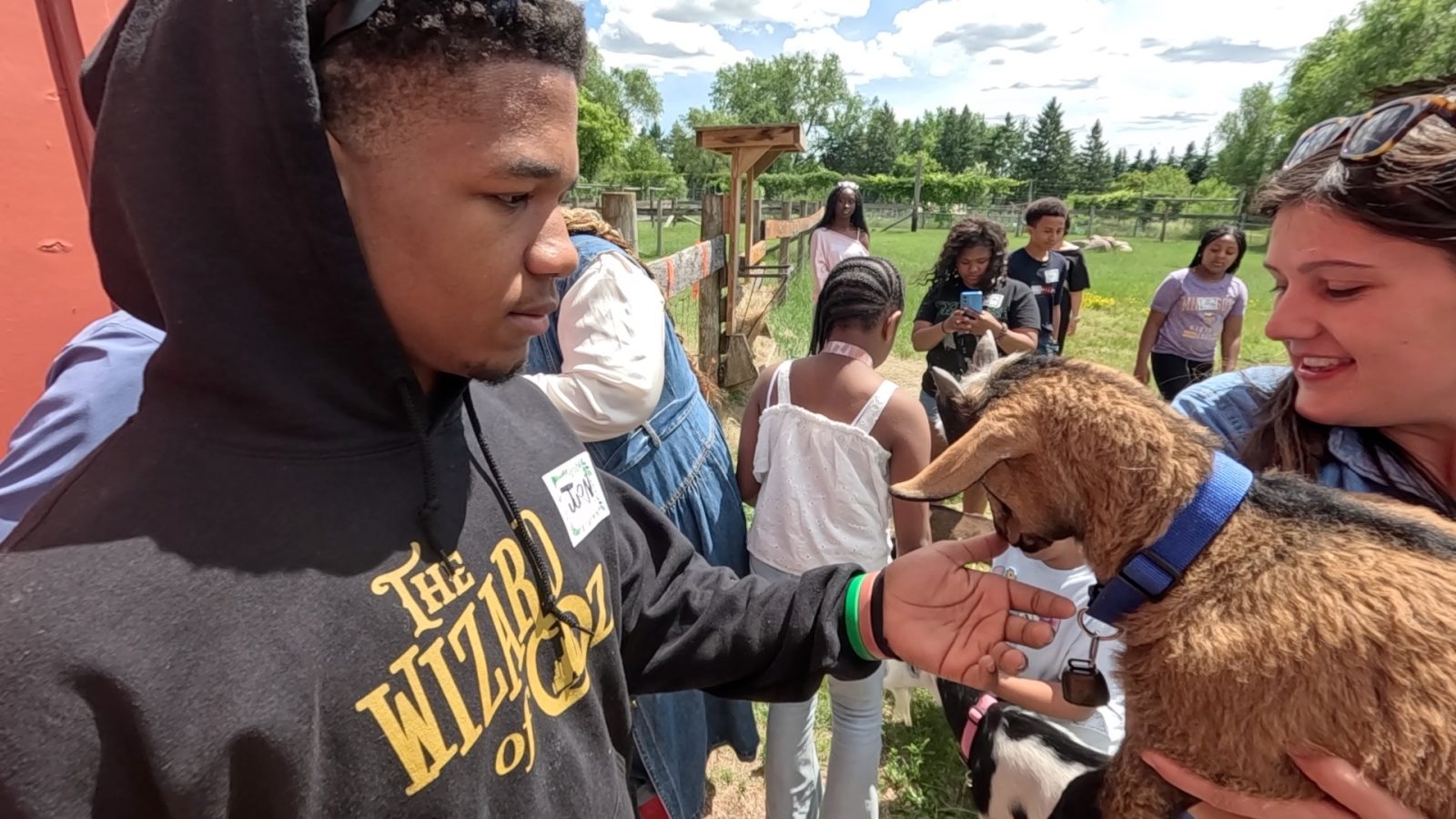 a young man pets a goat at a farm