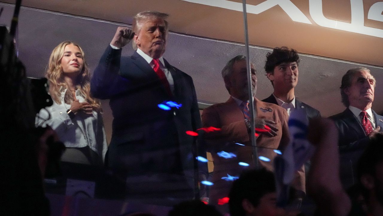 President Donald Trump gestures during the National Anthem as he attends an NBA Finals playoff basketball game between the New York Knicks and the San Antonio Spurs at Madison Square Garden in New York, Monday, June 8, 2026, with Kai Trump, left, Knicks owner James Dolan and Interior Secretary Doug Burgum, right. (AP Photo/Mark Schiefelbein)