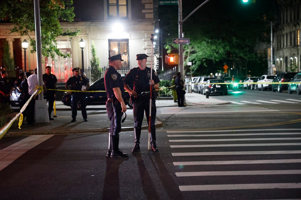 Police officers stand at an intersection at night, marked by yellow tape, following an accident where two children were struck by a vehicle.