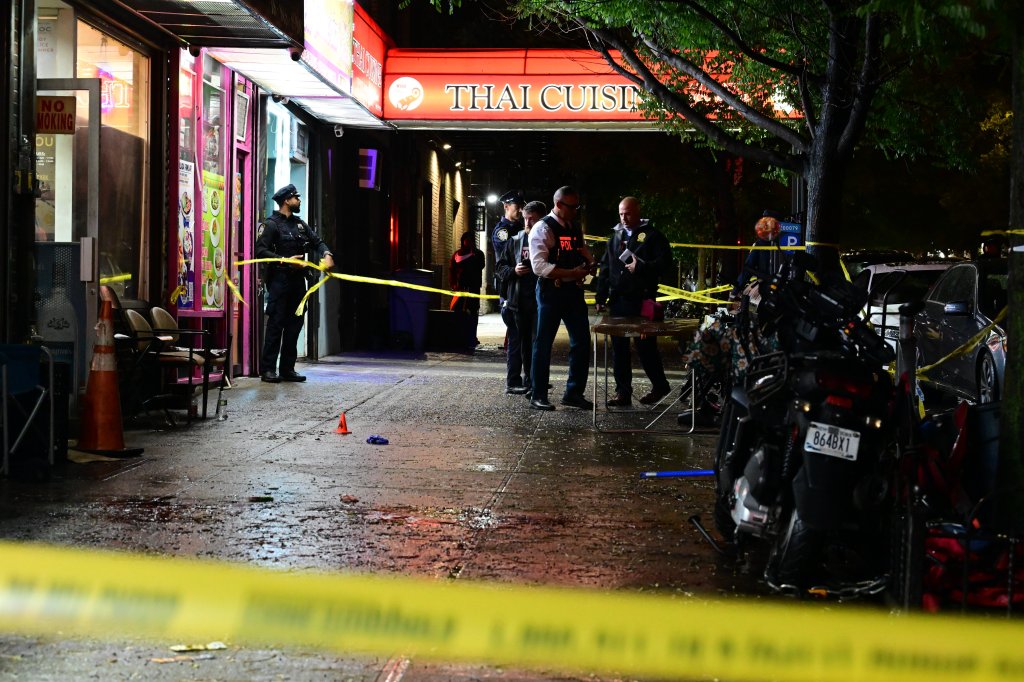 NYPD officers and emergency personnel work at the scene of a shooting in the Bronx, New York, with crime scene tape visible.