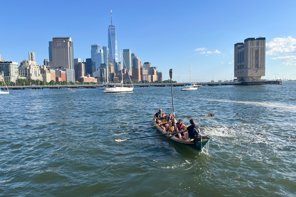 Members of the Village Community Boathouse row homemade vessels on the Hudson River,