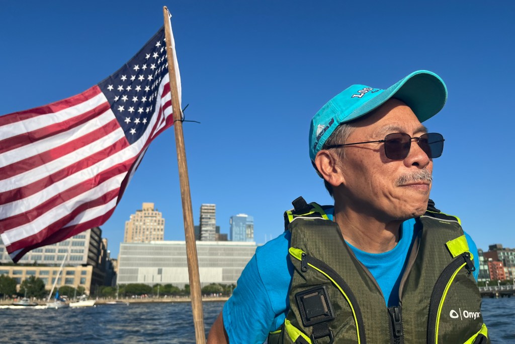 Phil Yee helps steer a boat in the Hudson River off the coast off the West Village