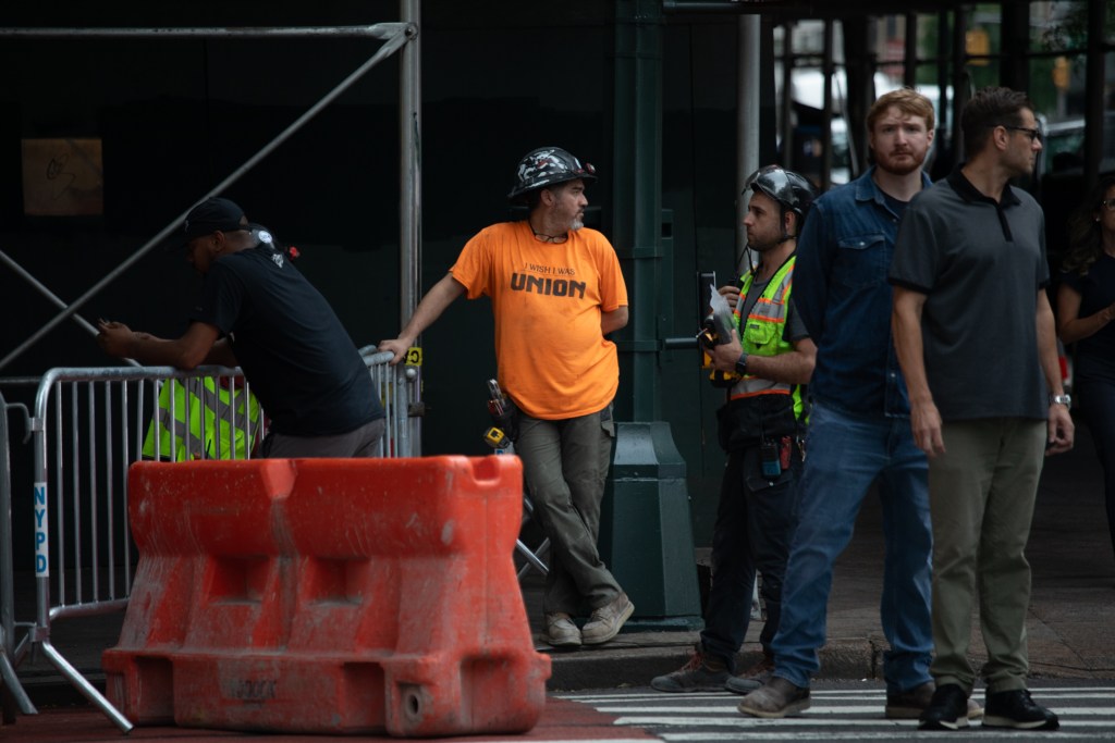A construction worker wears a shirt supporting unions outside the Pfizer Building after workers were forced to evacuate when support beams were found bent