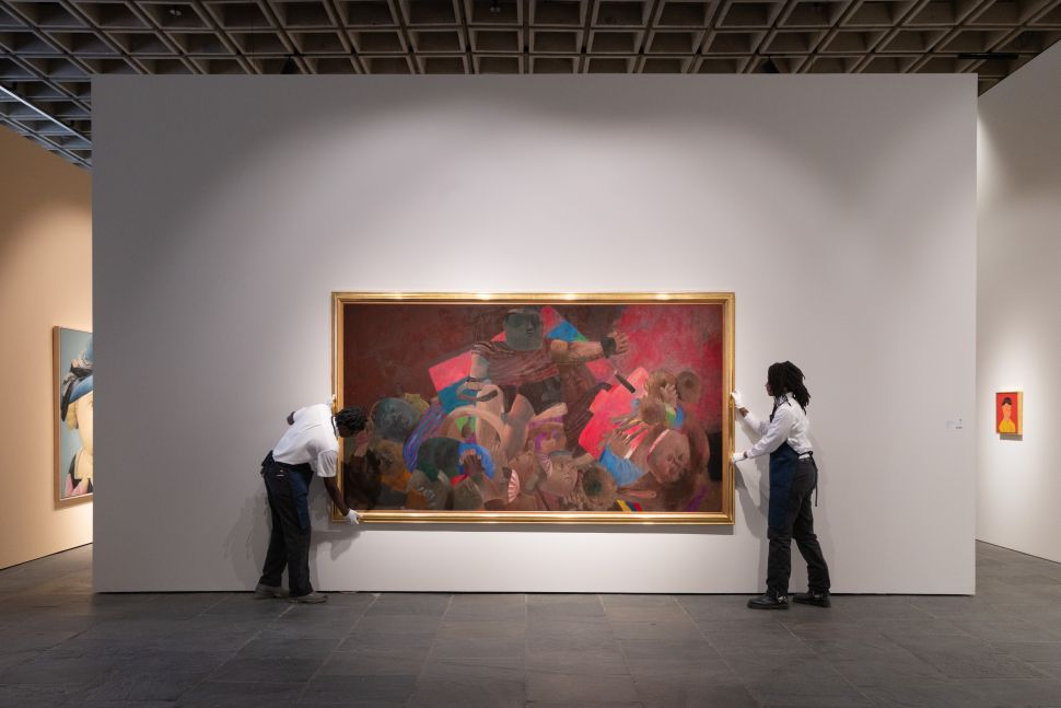 A brightly colored still life of sliced watermelon and assorted fruit hangs in a modern gallery as a blurred visitor passes beside it.