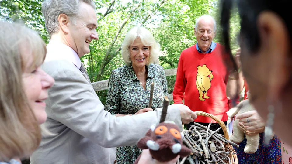 Queen Camilla, Patron of the Royal Literary Fund, and Gyles Brandreth (right) play a game of pooh sticks on Poohsticks Bridge during a visit to Ashdown Forest, to commemorate 100 years since the publication of the first Winnie the Pooh book in 1926. Ashdown Forest was the inspiration for the original Hundred Acre Wood and former home of author, A A Milne.