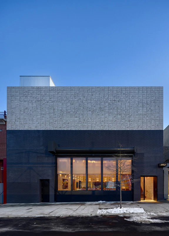 Modern building exterior with large windows, blue and gray facade, under a clear blue sky.