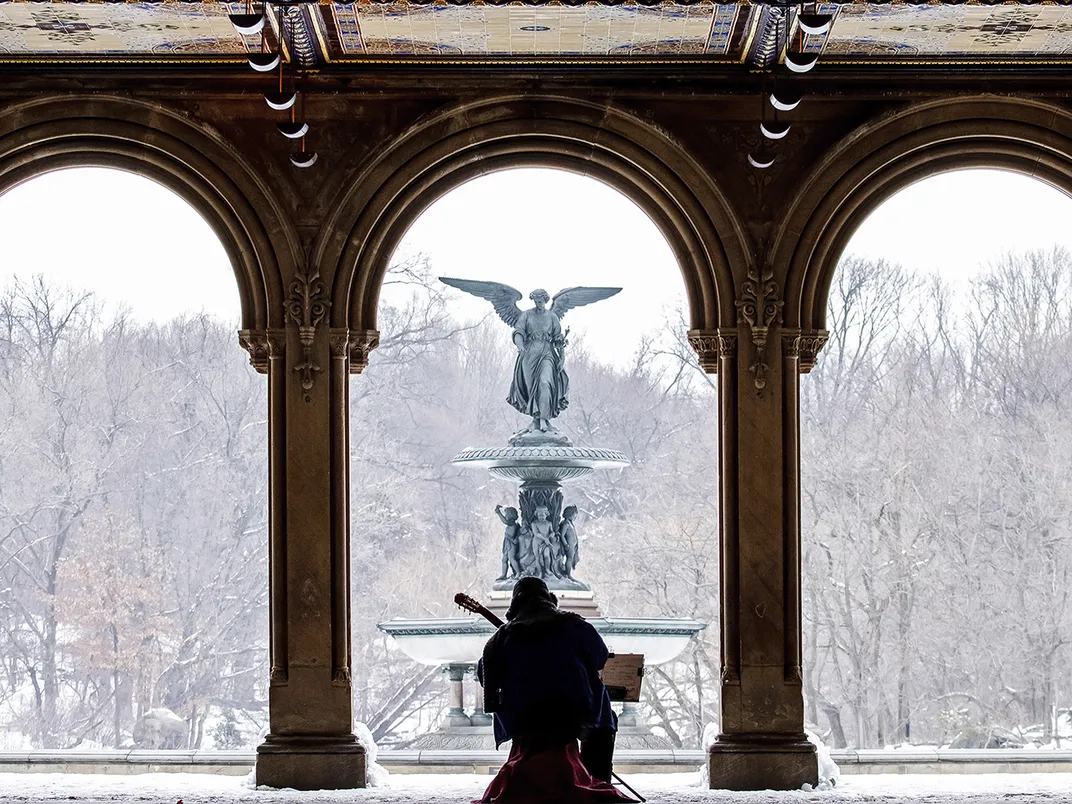 12 - Despite the weather, an artist with a perfect view of Angel of the Waters braves low temperatures to perform, perfectly framed by the arches of Bethesda Arcade.