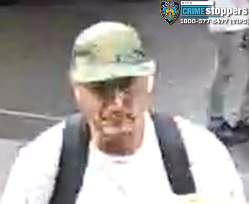 Surveillance image of a man in a camouflage hat and white shirt with a backpack.