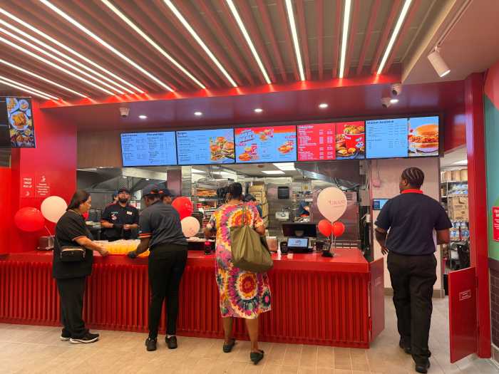 Jollibee staff prepare food to give away to customers waiting on line for entry.