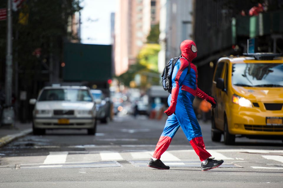 A man wearing a Spiderman costume is walking through the streets of Manhattan in New York City, USA.