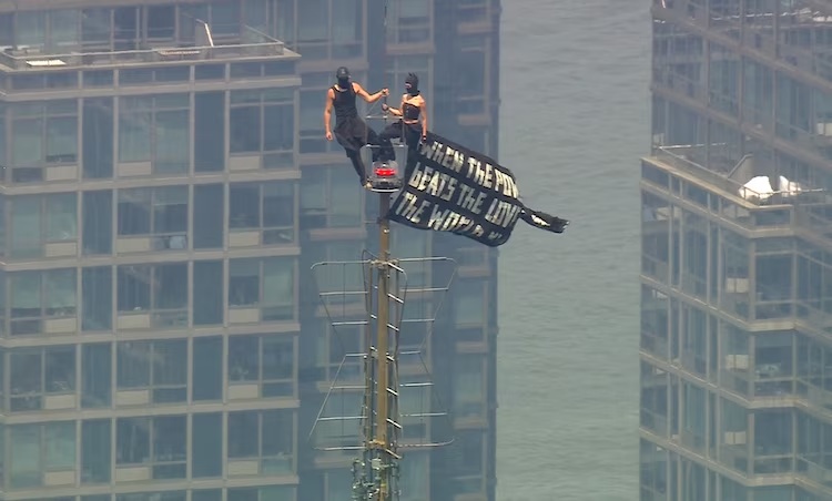 Angela Nikolau and Ivan Beerkus unfurl a banner at the top of the Empire State Building in New York City, July 1, 2026.