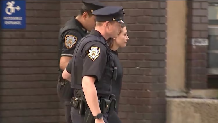 Angela Nikolau is seen being escorted out of a Manhattan police station, July 1, 2026.
