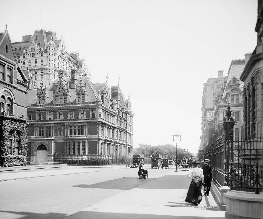 Vintage black and white photo of a busy Fifth Avenue in 1910, with people and horse-drawn carriages.