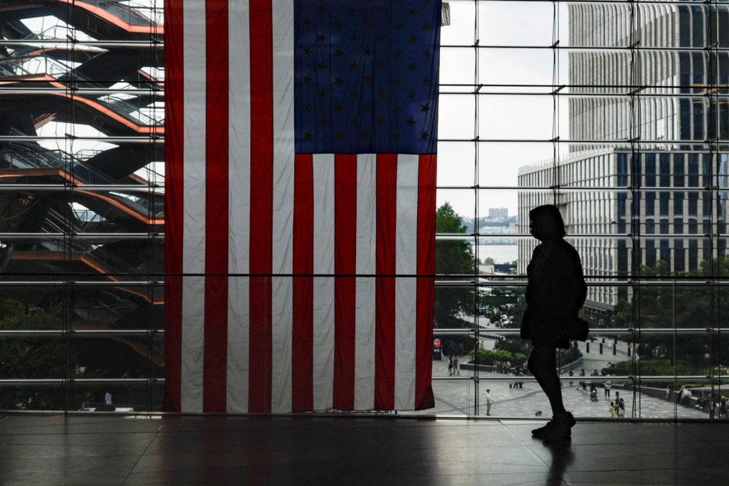 A shopper walks past a U.S. flag at Hudson Yards in New York City