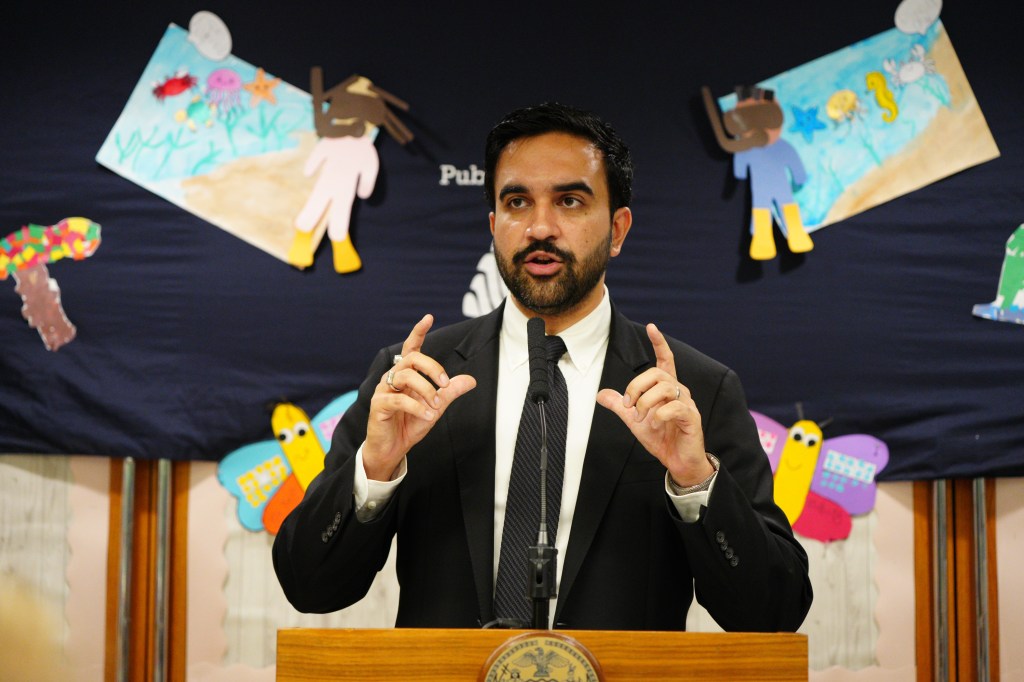 Mayor Zohran Mamdani speaks at a podium in front of children's drawings.