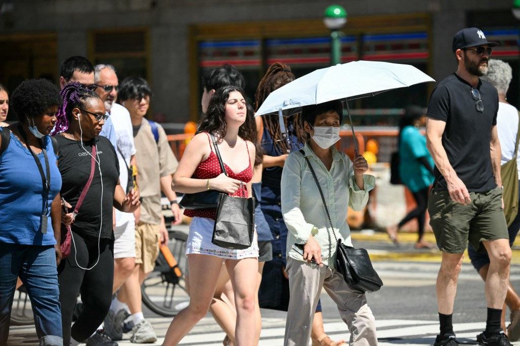 People cross a street in Midtown Manhattan during a heatwave.