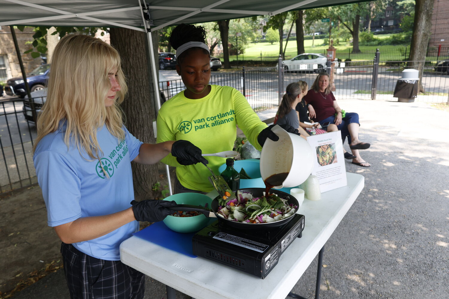 A July 15 cooking demo was led by Marin Rubin, 20, left, and Mariam Keita, 16, right. Fresh cabbage, carrot and onion sizzled on the pan as students offered samples of veggie stir fry, explaining it&rsquo;s an easy meal to make with rice, noodles or protein. Keita said she enjoys being an advocate for fair access to healthy food, especially in a neighborhood with few options.