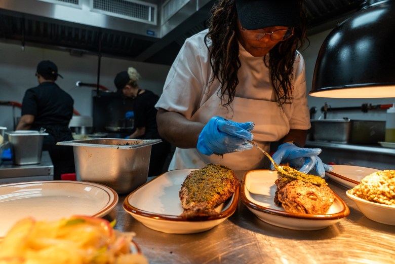 Chef Eva Volmar cooking in the kitchen of La Cachette du Coin restaurant in Brooklyn on Friday, May 29, 2026. Photo by Allison Hunter for The Haitian Times. 
