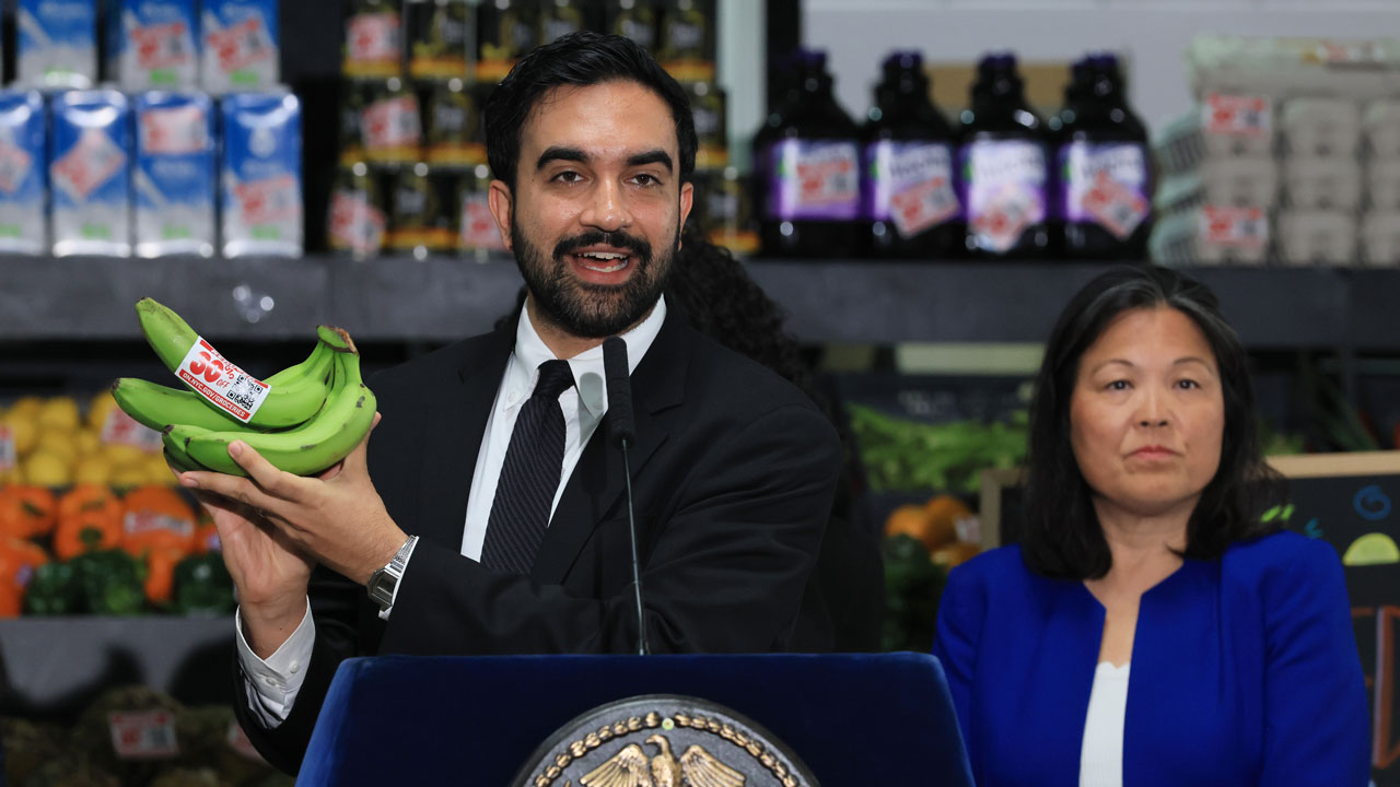 New York City Mayor Zohran Mamdani holds up bananas as he speaks at a food distribution center on July 27, 2026 in the Brooklyn borough of New York City. Mamdani announced that the five upcoming city-owned grocery stores will offer a 30 percent discount on produce, meat, bread, and milk when they begin to open next year. The discount on essential items will potentially save shoppers an estimated $90 a month, or roughly $1,000 a year, as prices for food and other items continue to rise throughout the country. The mayor has pledged one community grocery store for each borough. (Photo by Spencer Platt/Getty Images)