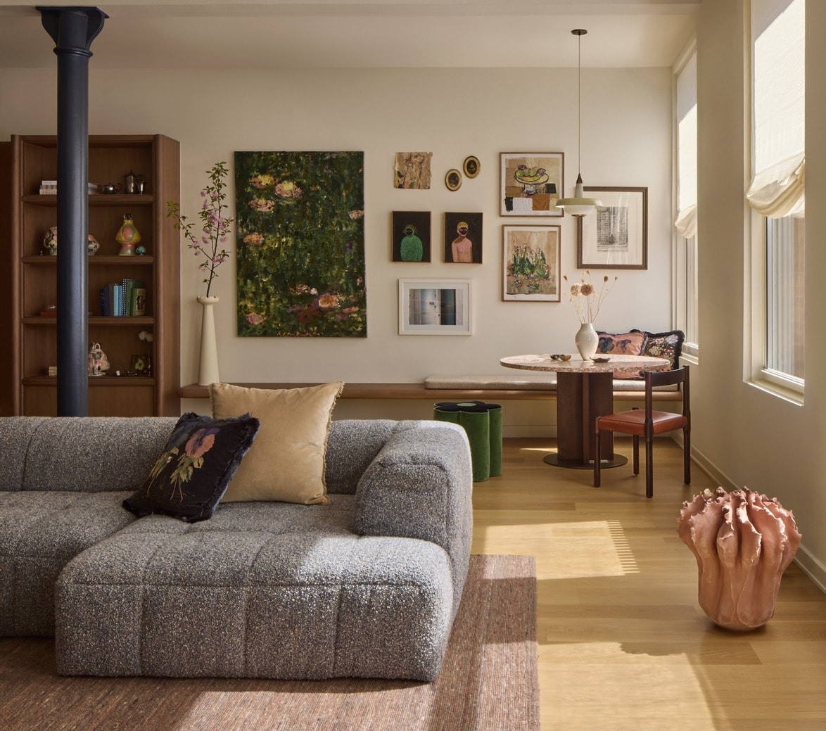 Cozy living room with a gray couch, artwork on the wall, and a round dining table by the window.