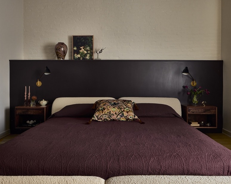 Cozy bedroom with a large bed, dark headboard, wall art, and decorative pillows.