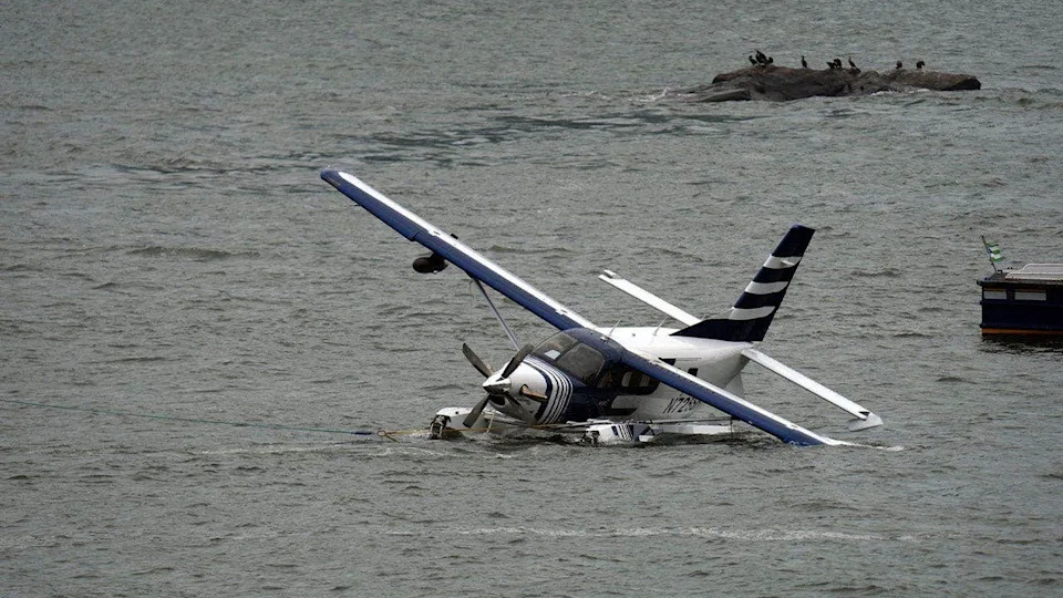 A seaplane sits partially submerged in New York City's East River after a hard landing