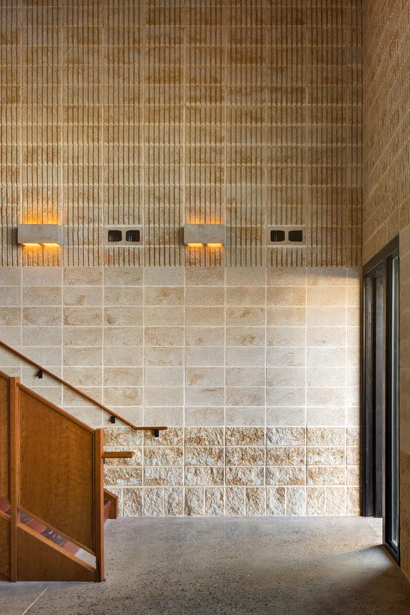 Modern interior with textured brick walls, wooden staircase, and warm ambient lighting.