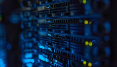 Server racks with illuminated indicators in a dimly lit data center.