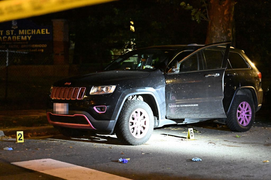Crime scene with a dark Jeep Grand Cherokee, its passenger door open, marked by evidence numbers 2 and 6 on the ground.