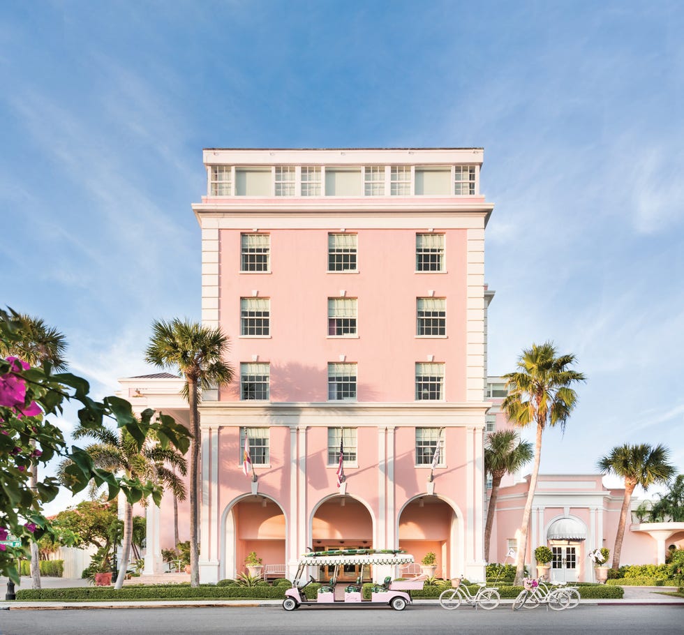 Historic pink hotel with palm trees and a bicycle rickshaw in front against a clear blue sky. Historic pink hotel with palm trees and a bicycle rickshaw in front against a clear blue sky.