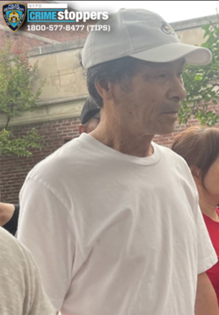 A man wearing a white t-shirt and white baseball cap, wanted for assault, looks to the right.