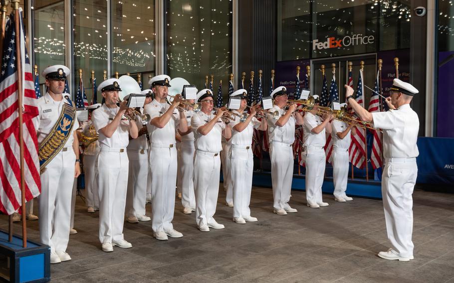 The band director stands in front and waves his arms as the band plays.