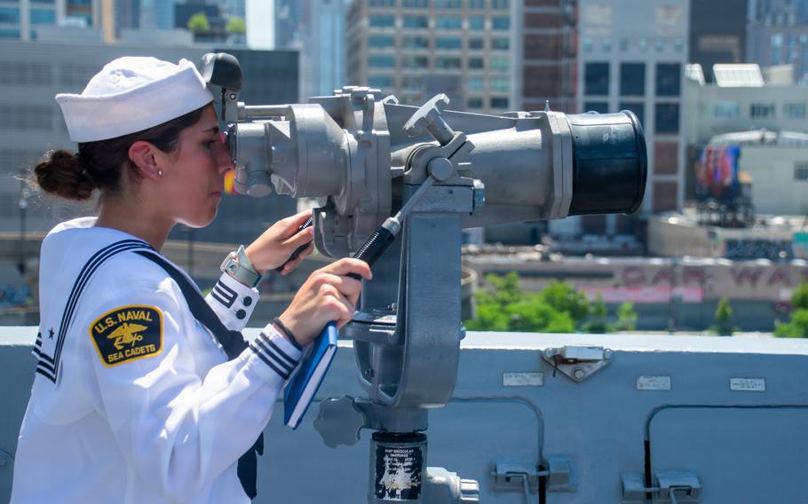 The sailor looks through the deck-mounted binoculars.