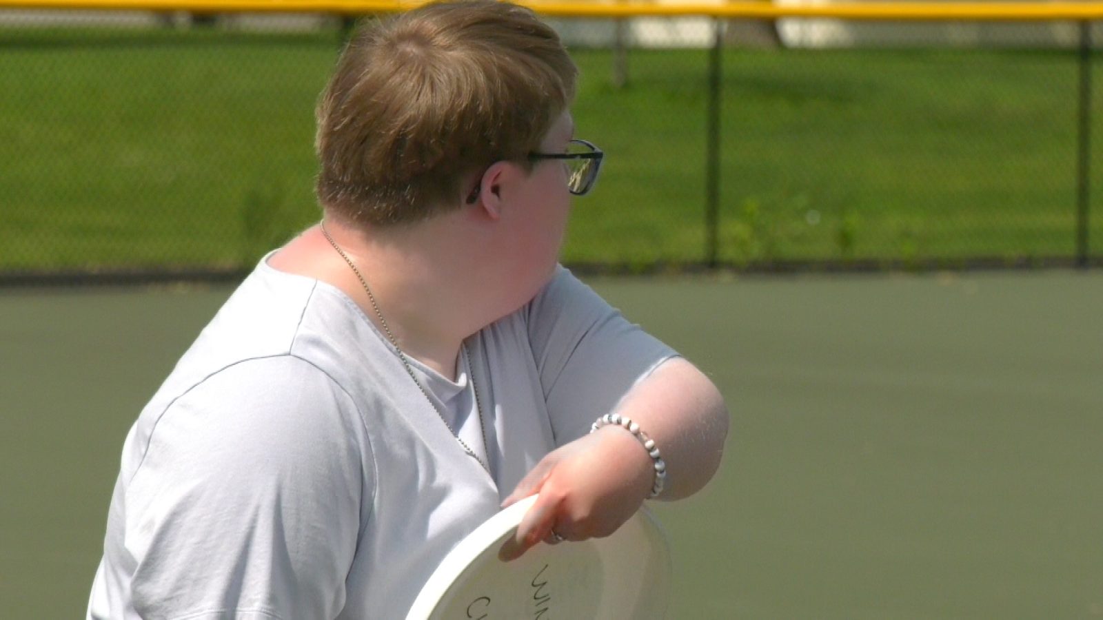 girl with short hair and glasses throws a frisbee
