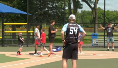 students and coaches stand on an adaptive softball field to practice frisbee