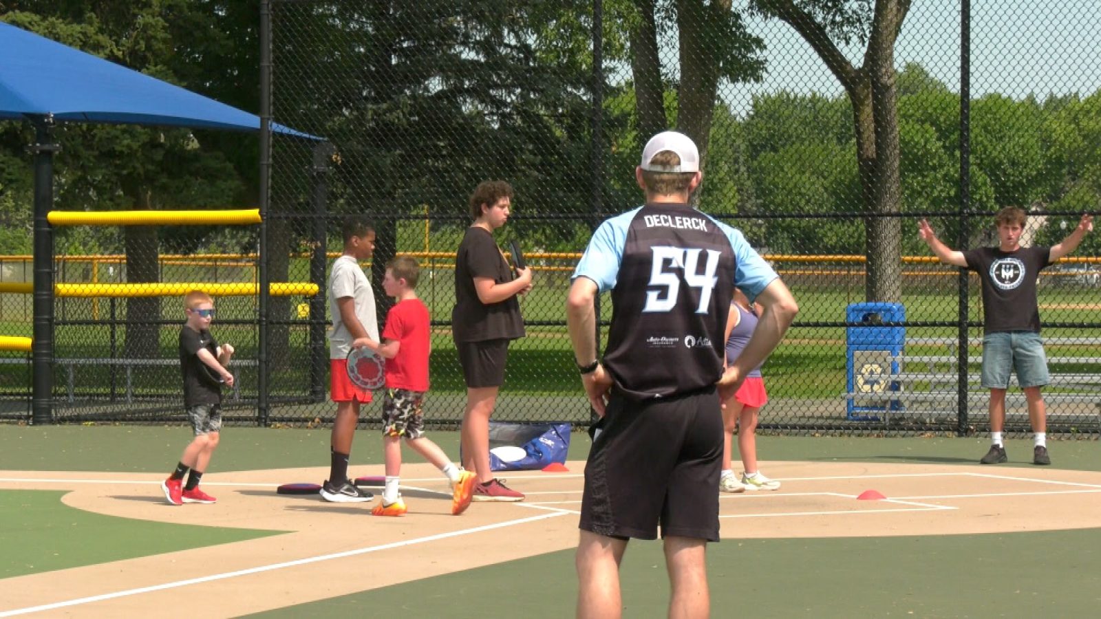 students and coaches stand on an adaptive softball field to practice frisbee
